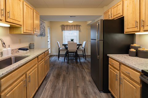 A kitchen with wooden cabinets and a black refrigerator.