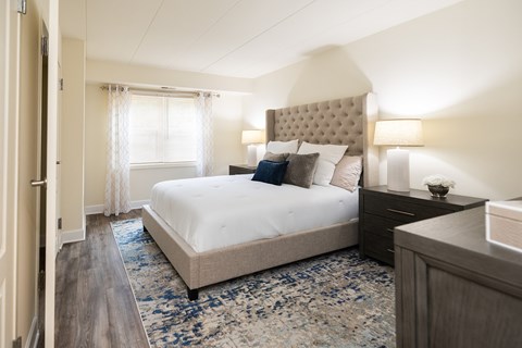 A bedroom with a large bed and a wooden dresser.