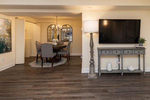 A living room with a television, a table, and chairs at Spring Hill Apartments & Townhomes, Baltimore, MD 21234.