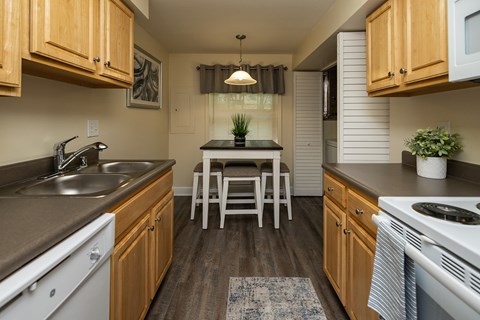 Eat-in kitchen with wooden cabinets and a dishwasher at Spring Hill Apartments & Townhomes, Baltimore, MD 21234.