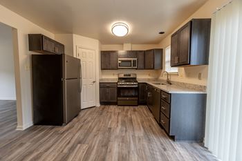an open kitchen with dark wood cabinets and stainless steel appliances at Carlson Woods Townhomes, Maryland, 21244
