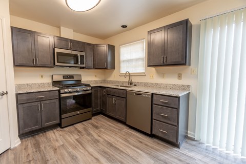a kitchen with dark wood cabinets and stainless steel appliances at Carlson Woods Townhomes, Maryland, 21244