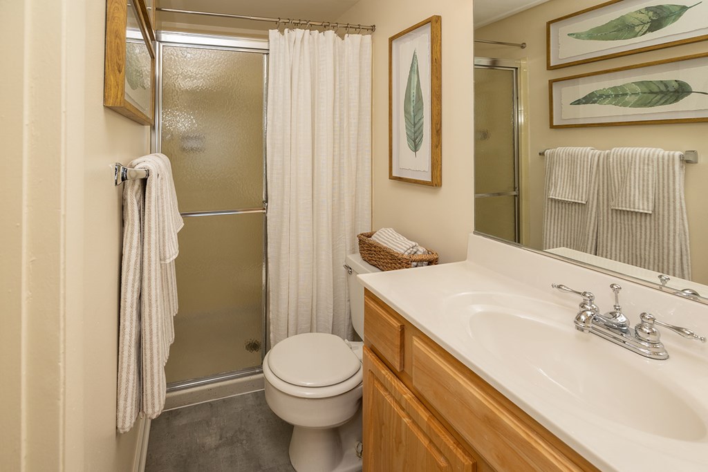 A bathroom with a toilet, sink, and shower at The Brittany Apartments, Pikesville, Maryland