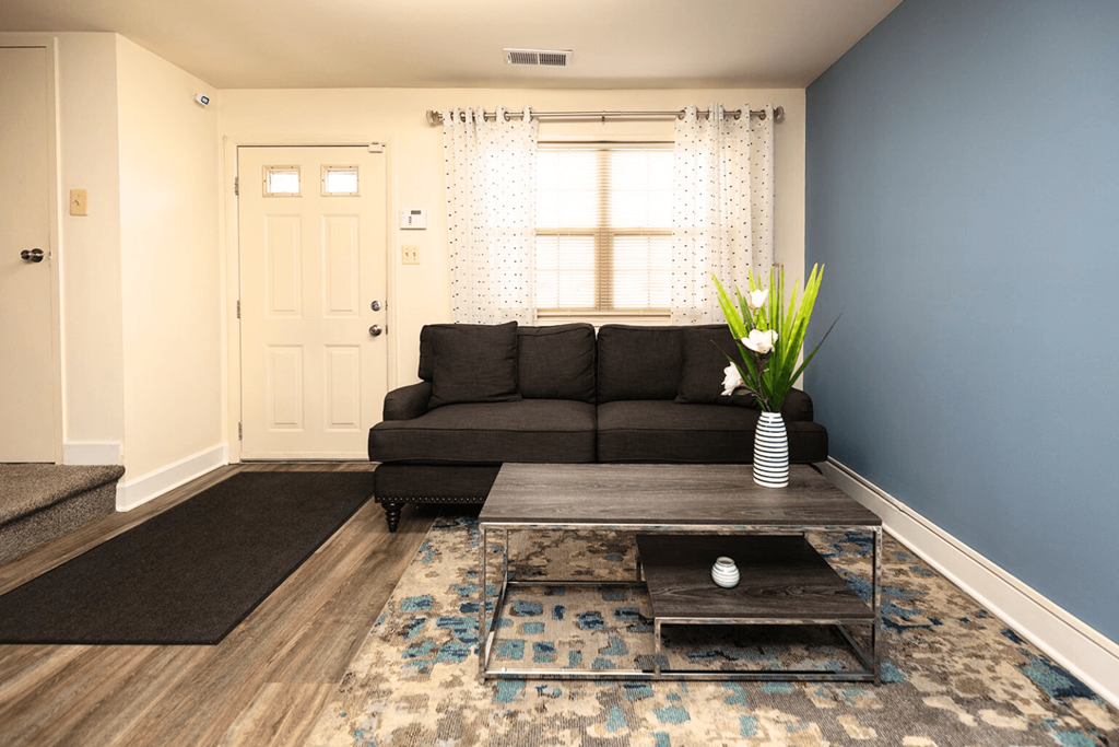 A living room with a grey couch, a coffee table, and a rug.