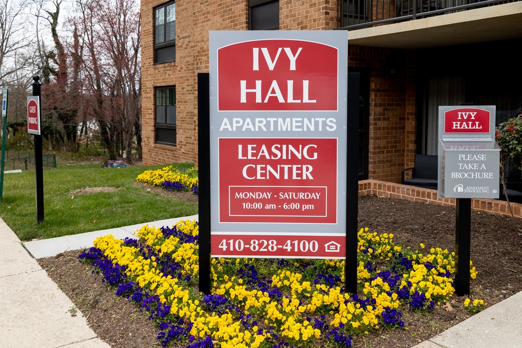 A sign for Ivy Hall Apartments leasing center is displayed in front of a building.