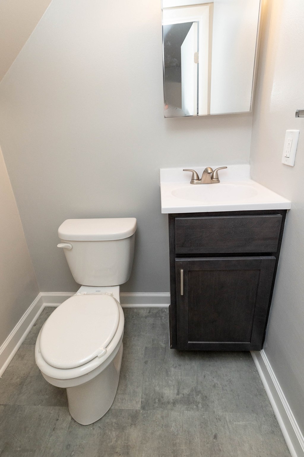 Small bathroom with a toilet sink and mirror at McDonogh Village Apartments & Townhomes, Randallstown, MD