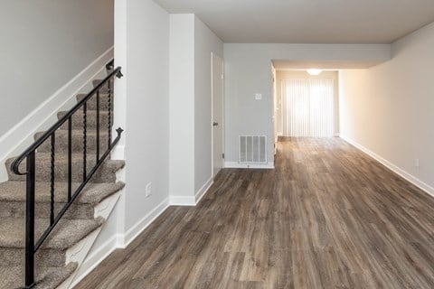 A living room with hardwood floors and a staircase at McDonogh Village Apartments & Townhomes, Randallstown