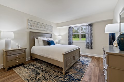 A bedroom with a large bed, a nightstand, and a dresser.
