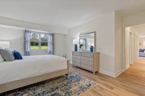 A bedroom with a large bed, a dresser, and a mirror.