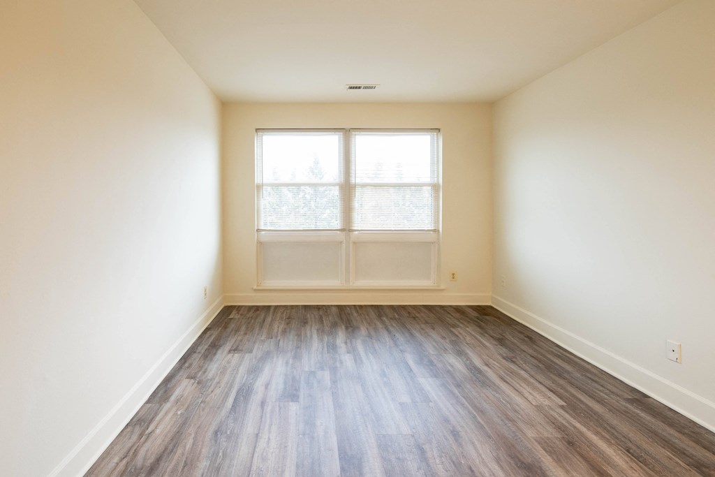 an empty room with white walls and wood floors  at Charlesgate Apartments, Towson, Maryland