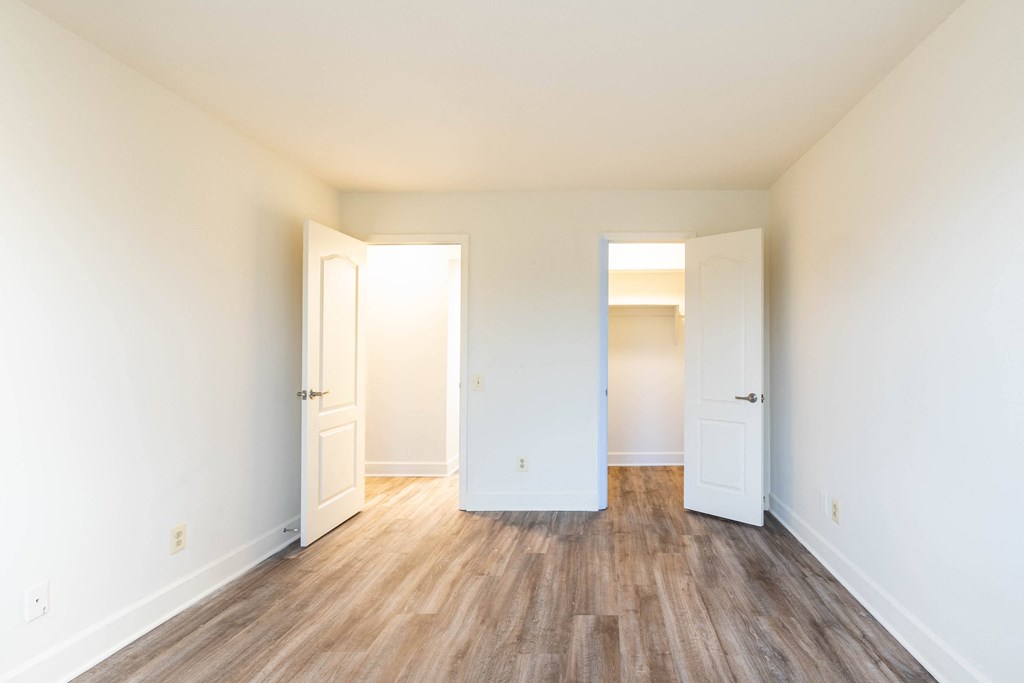 a bedroom with hardwood floors and white walls  at Charlesgate Apartments, Towson