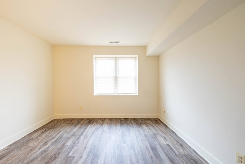 an empty room with white walls and wood floors  at Charlesgate Apartments, Towson
