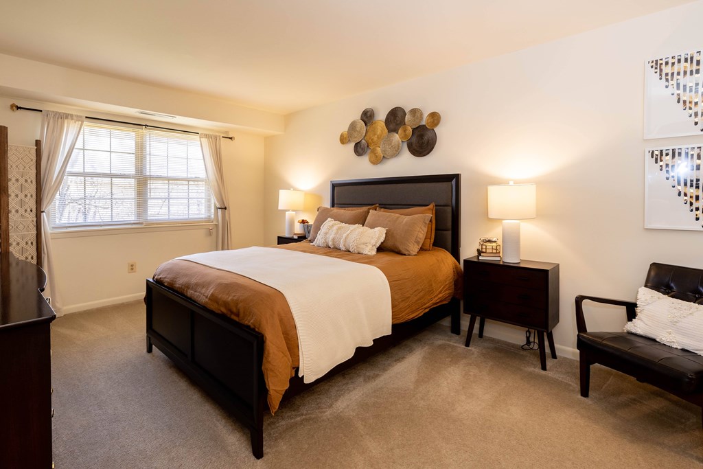 A bedroom with a large bed and a chair  at Village of Pine Run Apartments & Townhomes*, Maryland