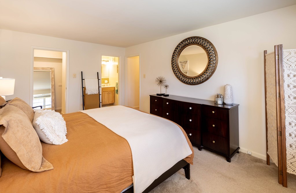 A bedroom with a bed, dresser, and mirror  at Village of Pine Run Apartments & Townhomes*, Maryland