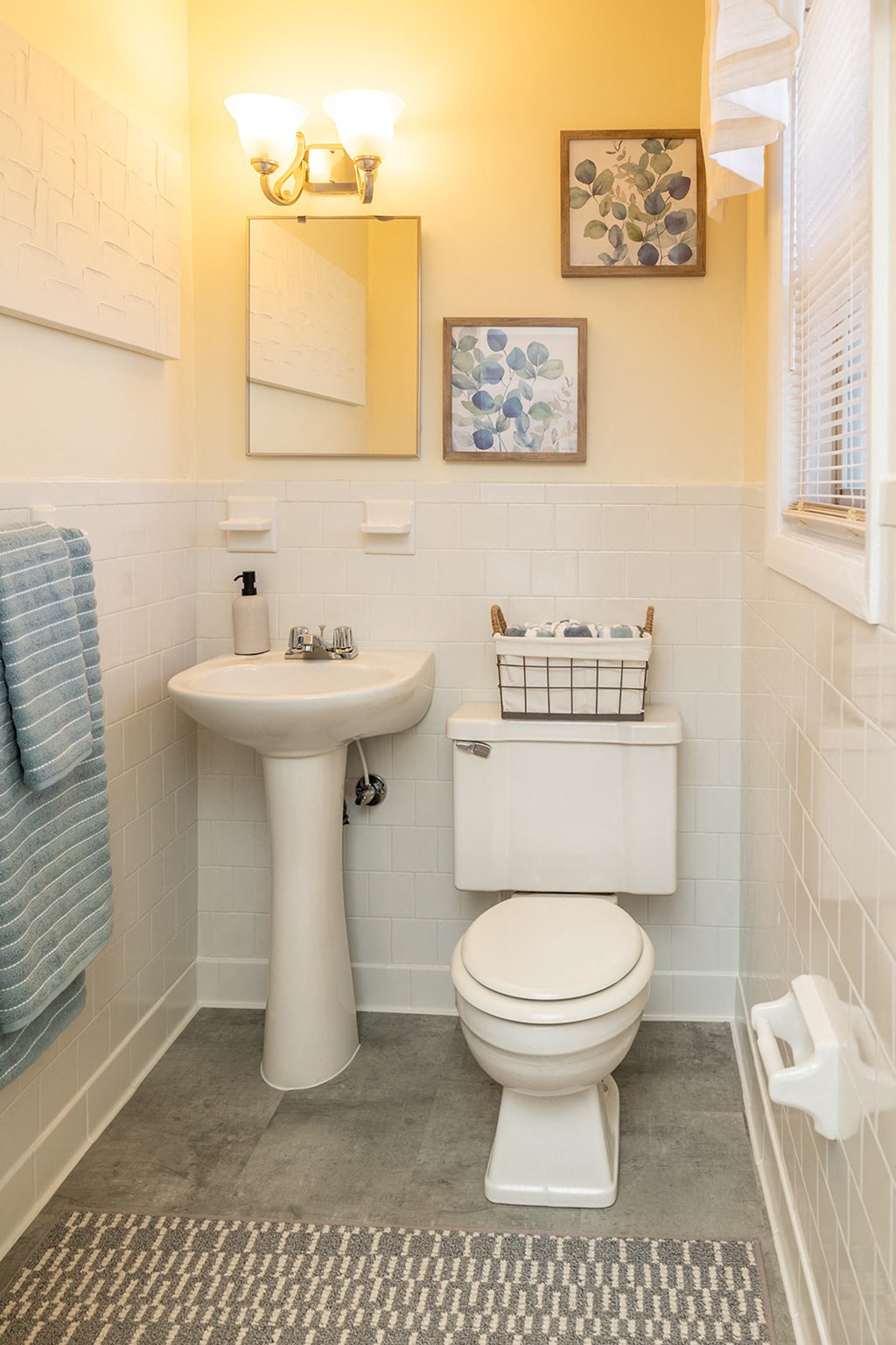 A bathroom with a toilet, sink, and mirror at Liberty Gardens Apartments, Baltimore