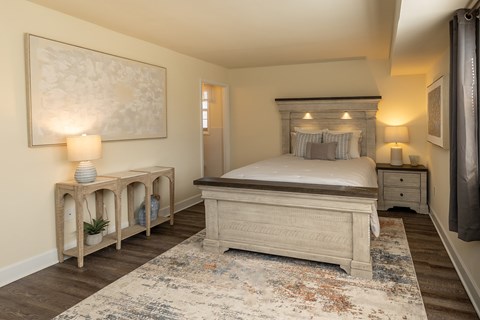 A bedroom with a large bed and a painting on the wall.