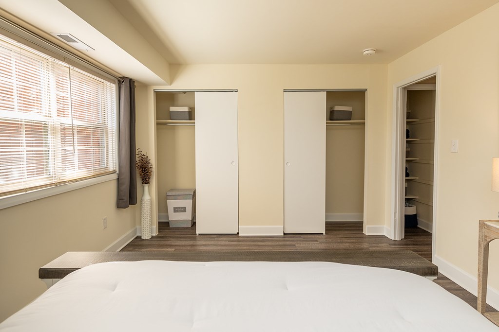 A bedroom with a large bed and a window with blinds. at Liberty Gardens Apartments, Baltimore, MD