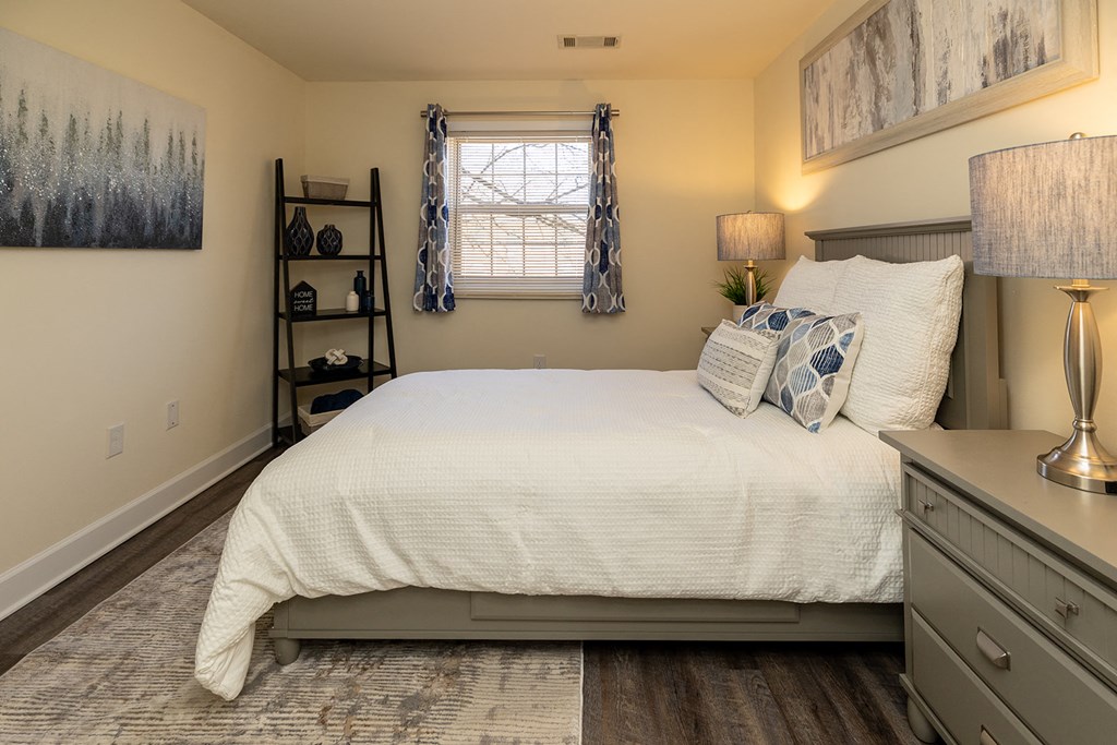 A bedroom with a white bed and a grey headboard at Liberty Gardens Apartments, Baltimore, MD, 21244