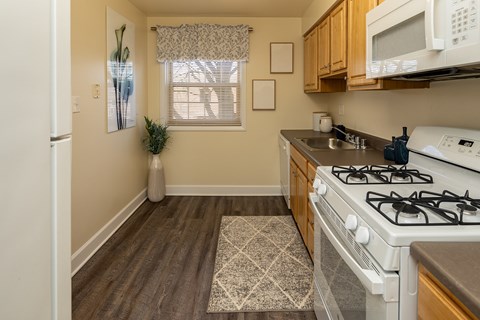 A kitchen with a white gas stove and wooden cabinets.