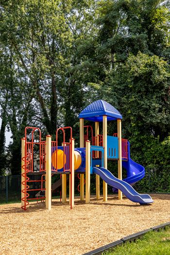 a playground with a swing set and slides at Seven Oaks Townhomes, Edgewood