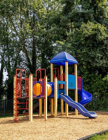 A playground with a blue slide and a yellow ball.