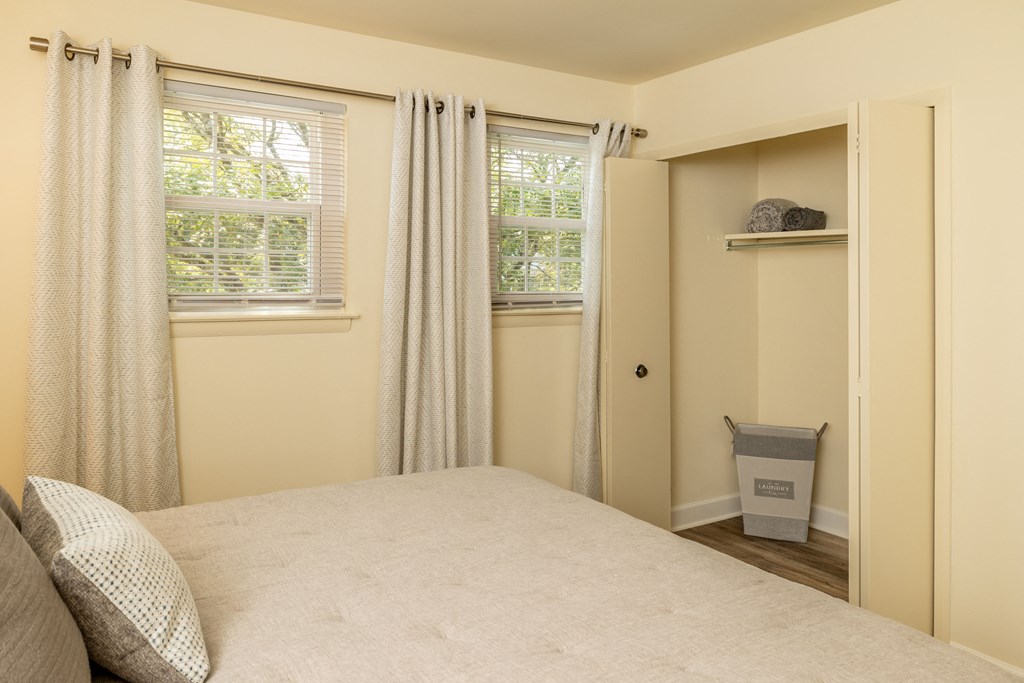 A bedroom with a bed, window, and a small closet.