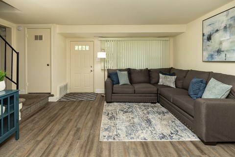 A living room with a brown couch and a blue rug at The Orchards at Severn Townhomes*, Severn, MD 21144.