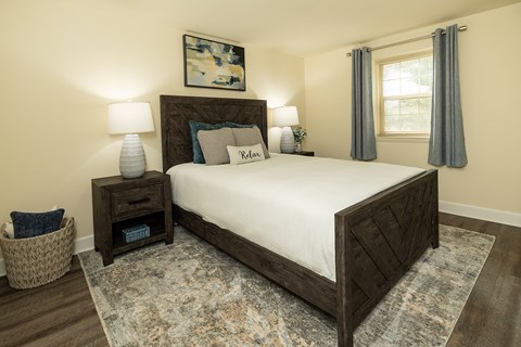 A bedroom with a large bed and a painting on the wall at The Orchards at Severn Townhomes*, Severn, MD 21144.