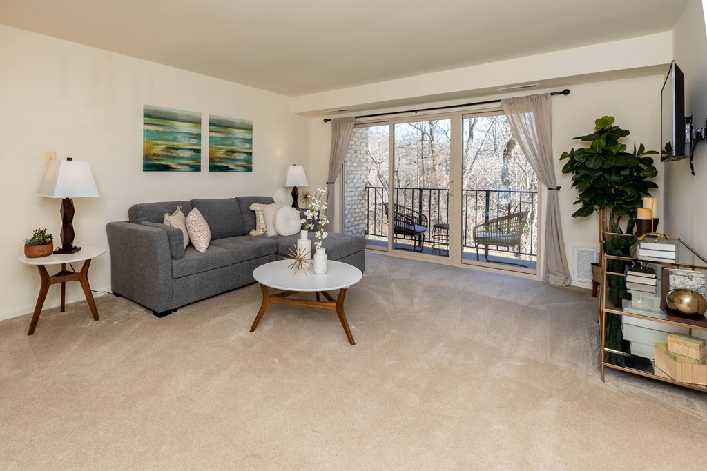 A living room with a grey couch, a white coffee table, and a painting on the wall  at Village of Pine Run Apartments & Townhomes*, Maryland