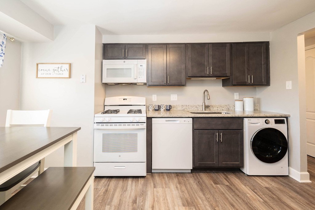A kitchen with dark wood cabinets and white appliances at Fairbrook Park, Baltimore, 21244