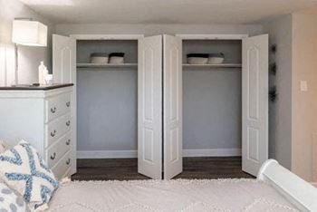 A bedroom with a bed and a dresser with a lamp on it at Fairbrook Park Apartments in Baltimore, MD