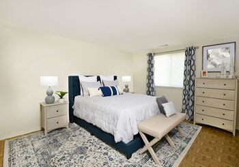a bedroom with a bed with white and blue bedding and two night stands with lamps on at Winston Apartments, Maryland