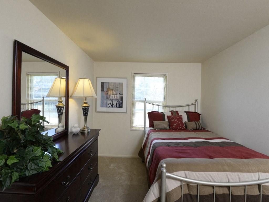 a bedroom with a bed and a dresser with a mirror at Yorktowne Townhomes Apartments, Hanover, PA 17331
