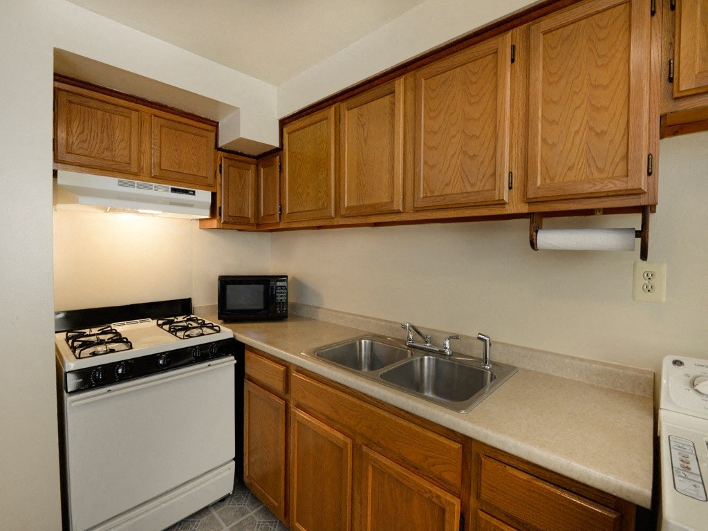 Kitchen with wooden cabinets and white appliances at Yorktowne Townhomes Apartments, Pennsylvania