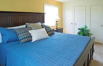 Bedroom with a bed with blue sheets and pillows at Security Park Apartments*, Windsor Mill, MD, 21244