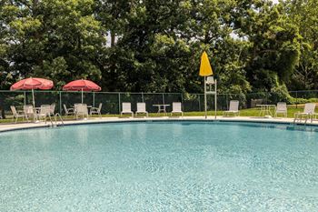 Swimming pool with chaise lounge chairs and umbrellas at Security Park Apartments*, Windsor Mill, MD, 21244