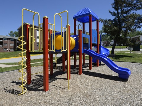 A playground with a blue slide and yellow and red play structures at Colony Hill Apartments & Townhomes, Baltimore, MD