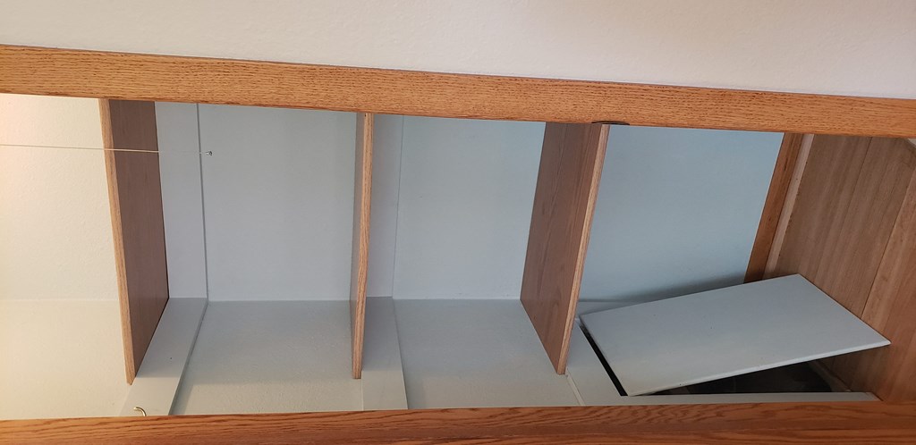 an empty shelf in a closet with a mirrored door