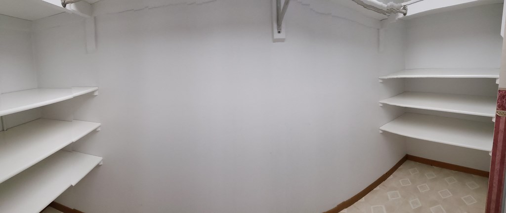 a small room with white shelves and a white wall