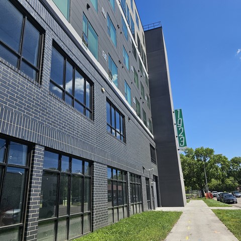 A modern building with a grey facade and a green sign on the right side.
