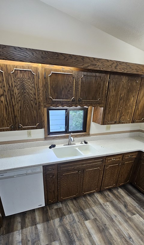 A kitchen with wooden cabinets and a white dishwasher.