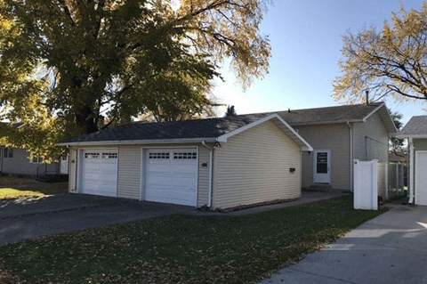 a white house with two garage doors and a tree