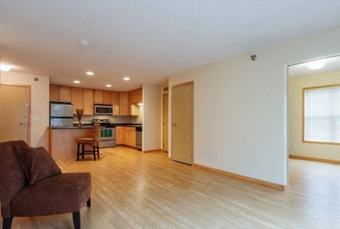 A brown couch is in a living room with a kitchen in the background.