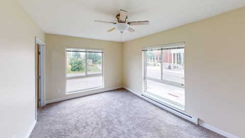 A room with a ceiling fan and two windows.