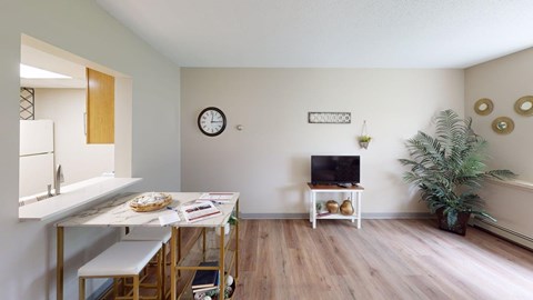 A room with a table, a clock, a television, and a plant.