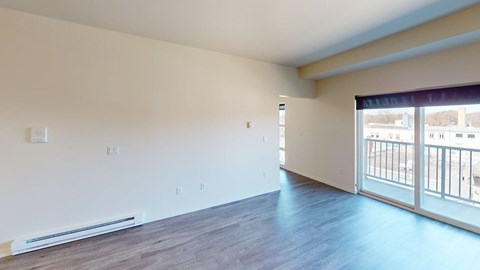 A spacious room with a sliding glass door leading to a balcony.