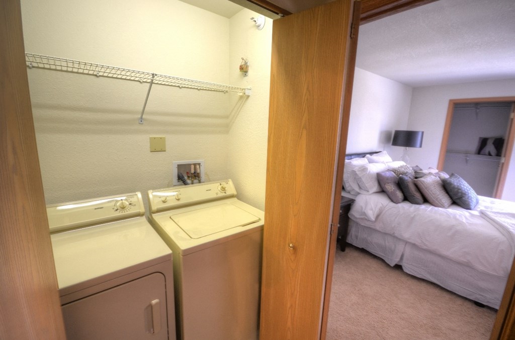 a bedroom with a washer and dryer next to a bed