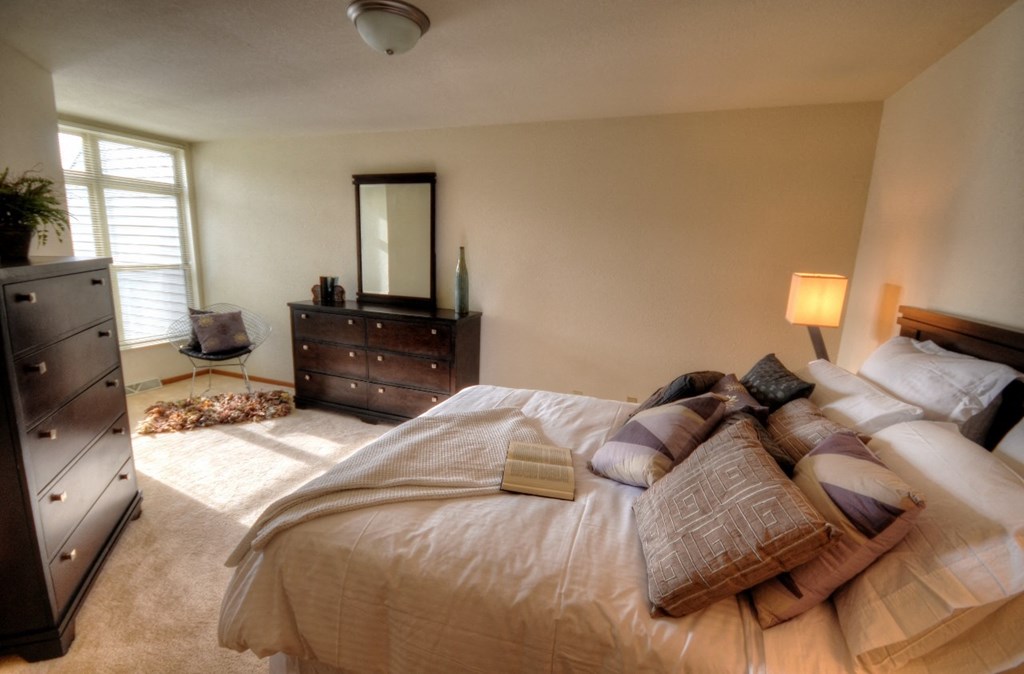 a bedroom with a bed and a dresser and a window