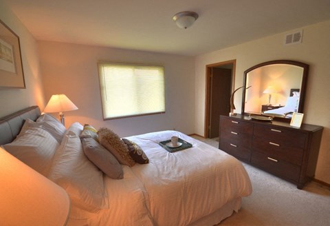 a bedroom with a bed and a dresser and a mirror