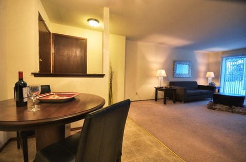 a living room and dining room with a table and a bottle of wine